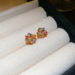 Close-up of colorful flower stud earrings with vibrant crystal petals on velvet