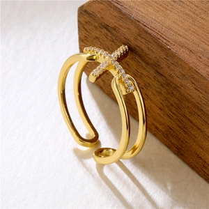 Golden criss-cross ring with sparkling cubic zirconia on a minimalist wood display