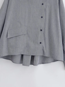 Detail of black and white plaid shirt showing button closure and irregular curved hem