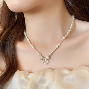 Detailed close-up of a sparkling zircon bow pendant on a French style pearl necklace