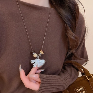 Ginkgo leaf pendant necklace with wooden beads and rope chain shown on a model
