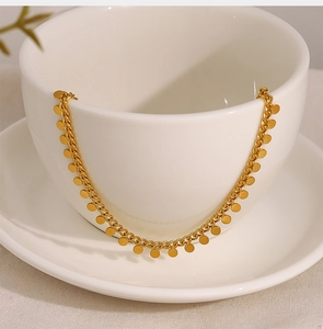 Close-up of golden disk pendant necklace draped over a minimalist white ceramic cup