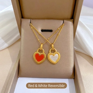 Detail of double-sided heart pendant necklace in gold featuring red and white shell inlay