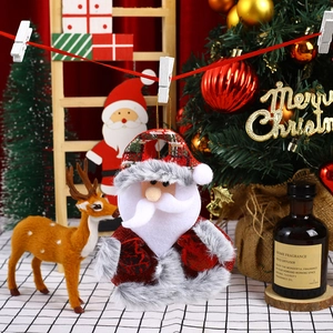 Close-up of plush Santa Claus ornament with tartan hat in a festive holiday setting
