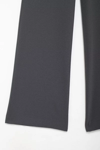 Detailed close-up of dark grey wide-leg trousers showing premium fabric texture and hem