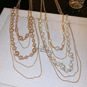 Detail of layered faux pearl necklaces in champagne and white on a jewelry tray