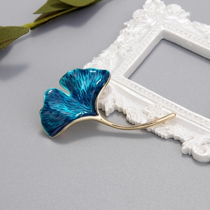 Macro shot of ginkgo leaf brooch with blue gradient enamel and golden metallic base