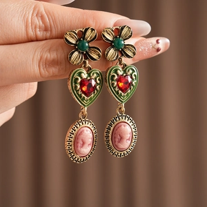 Détail de boucles d'oreilles cœur vintage avec relief de pierres et camées portrait