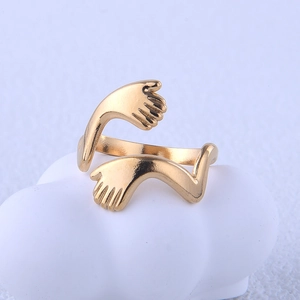 Vue détaillée d'une bague mains qui s'enlacent en acier doré sur un décor blanc