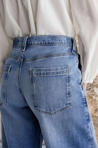 Détail des poches arrière et coutures renforcées sur un jean en denim brodé bleu clair