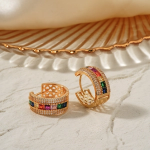 Elegant gold huggie earrings featuring vibrant rainbow cubic zirconia on a silk background