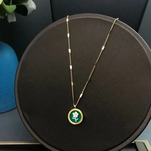 Vue détaillée du collier fleur doré avec un pendentif rond en émail vert et blanc