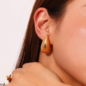 Detail of hollow waterdrop earring with golden spiral texture on model ear