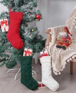 Close-up of three knitted Christmas stockings in red, green, and white hanging by a tree