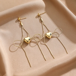 Detail of gold-plated titanium steel long tassel earrings with polished heart charms