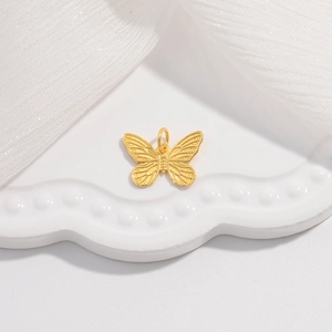 Golden butterfly pendant with textured wings on a white decorative porcelain plate