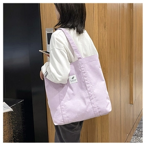 Detailed view of lavender corduroy tote bag with woven label and thick dual straps