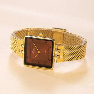 Close-up of square quartz watch with brown dial and golden mesh band on warm background