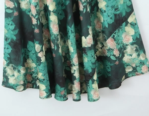 Dettaglio vestito verde scuro con stampa floreale di rose e orlo ondulato in chiffon