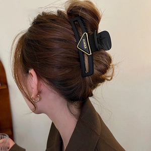 Matte black triangle hair claw clip with golden POWER letter ornament on a model