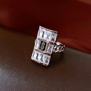 Dettaglio macro dell'anello rettangolare con logo S argento su smalto nero e fascia a catena