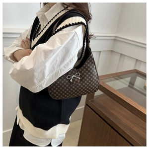 Detail of vintage patterned underarm bag featuring a silver bow buckle and shoulder strap