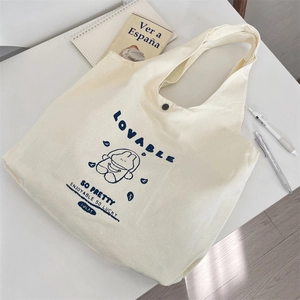 Detail shot of canvas tote bag featuring cute cartoon bear print and secure snap closure