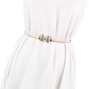 Détail de la ceinture dorée élastique avec nœud en strass sur une robe blanche élégante