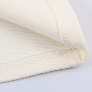 Detailed close-up of cream knit fabric stitching and hemline on a sleeveless crop top