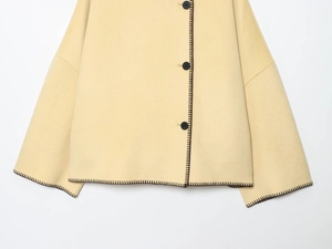 Detail of beige wool coat featuring black contrast stitching and round button closure