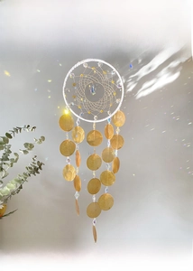 Detail of a Nordic style dreamcatcher with shell discs and crystal beads on white wall