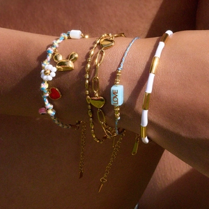 Bracelets multicouches en or et perles avec breloques cœur et fruits au poignet