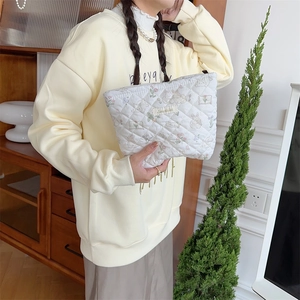 Quilted white cosmetic bag featuring cute hand-drawn cartoon prints and zip closure