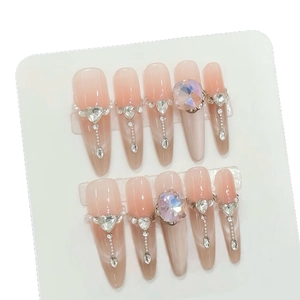 Handmade press-on nails with nude cat eye gradient, heart crystals, and tassel gems