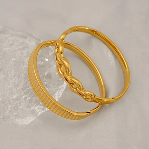 Close-up of gold plated stainless steel bangles with striped and chain-link texture detail