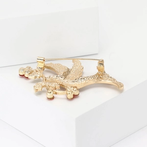 Detail view of the gold pigeon brooch back featuring pin fastener and red gemstone