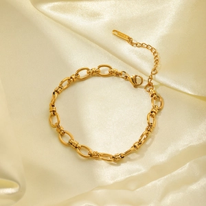 Close-up of polished 18K gold plated chain bracelet with lobster clasp on silk fabric
