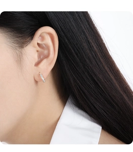 Close-up of minimalist silver and rose gold intertwined hoop earrings worn by a model
