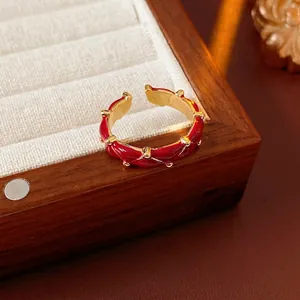 Elegant gold plated open ring with red enamel and vintage twisted texture on wood box
