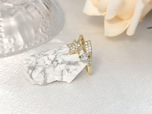 Detail of gold star ring with micro-pave diamonds and round stone on marble background