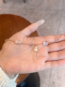 Macro detail of rose gold gourd bracelets with white shell and zircon inlays on hand