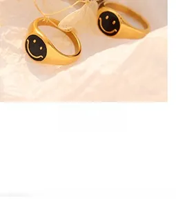 Close-up of golden stainless steel band rings with black enamel smiley face design