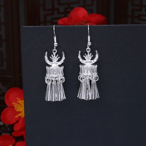 Detail of silver ethnic earrings featuring traditional drum motif and long tassels