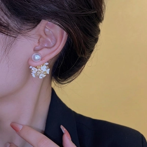 Boucles d'oreilles élégantes avec perles et fleurs blanches portées par un mannequin