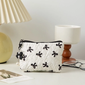 Close-up of heart quilted makeup bag featuring black bow prints and pearl pendant