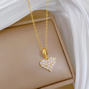 Elegante Halskette aus Gold-Titanstahl mit glitzerndem Herzanhänger auf Seidenstoff