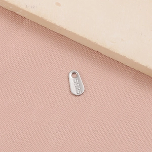 Macro shot of S925 sterling silver teardrop charm with engraved hallmark on a stone