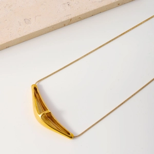 Collier minimaliste en or avec pendentif géométrique et chaîne serpent sur fond de marbre