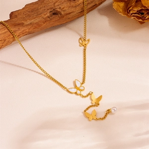 Detail of golden butterfly necklace with pearl tassel and white inlay on branch