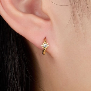 Close-up of a gold s925 silver hoop earring with a sparkling star-shaped zircon pendant